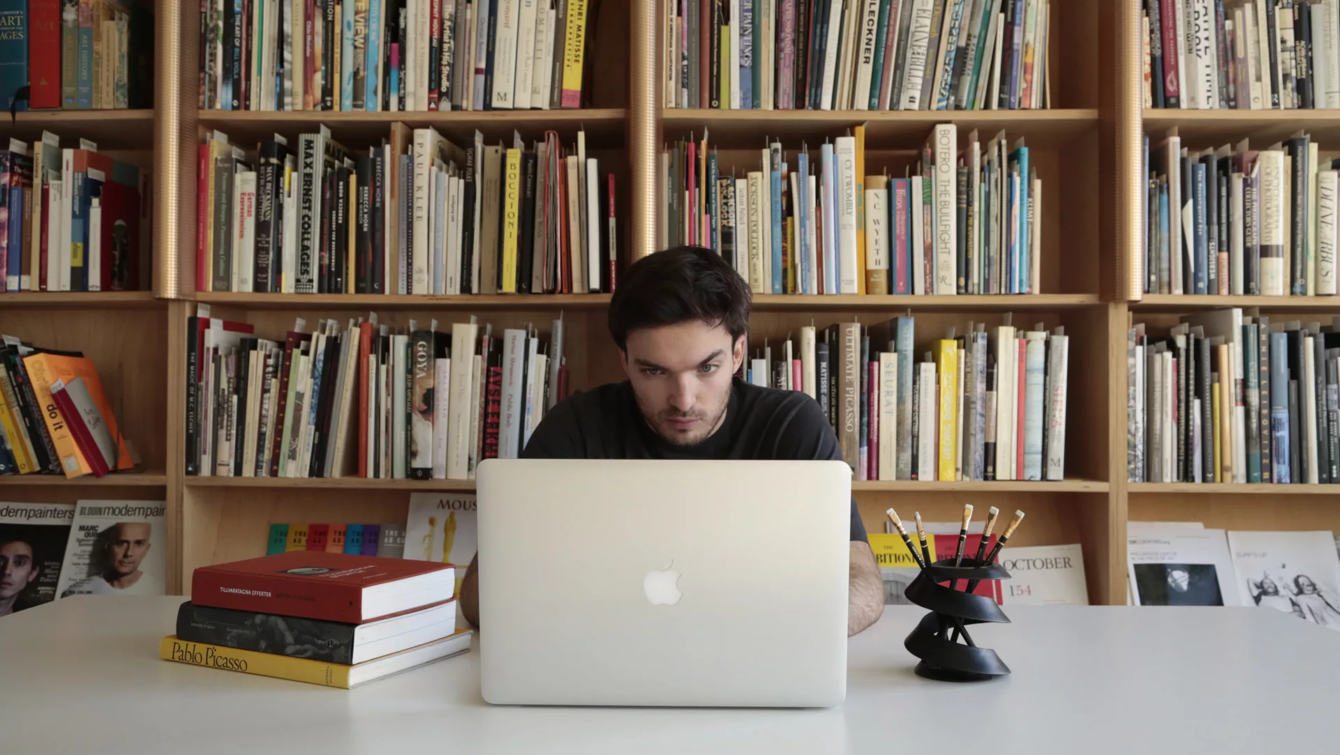 A curvas on a library table, with a human working in the background.