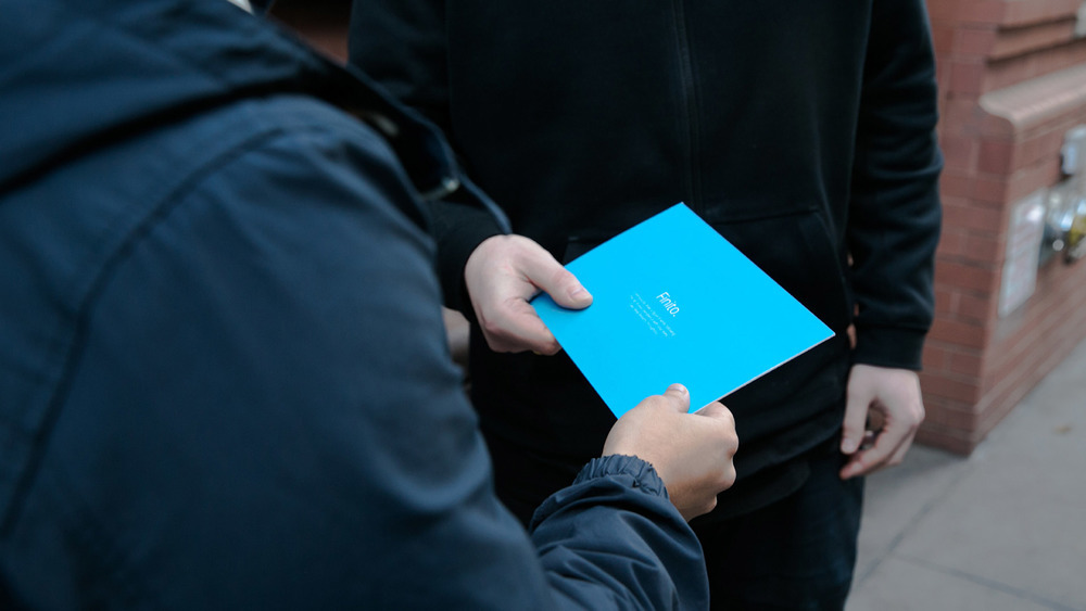 A human handing a Finito card to another human on the street.