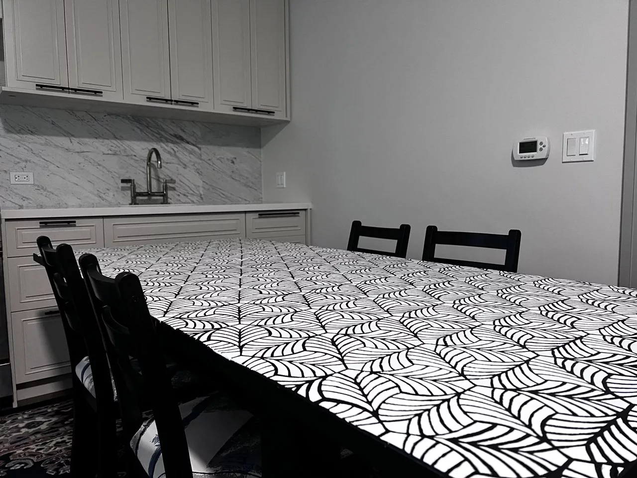 A table with an endlessly repeating pattern formed by a single leaf within a modern kitchen.