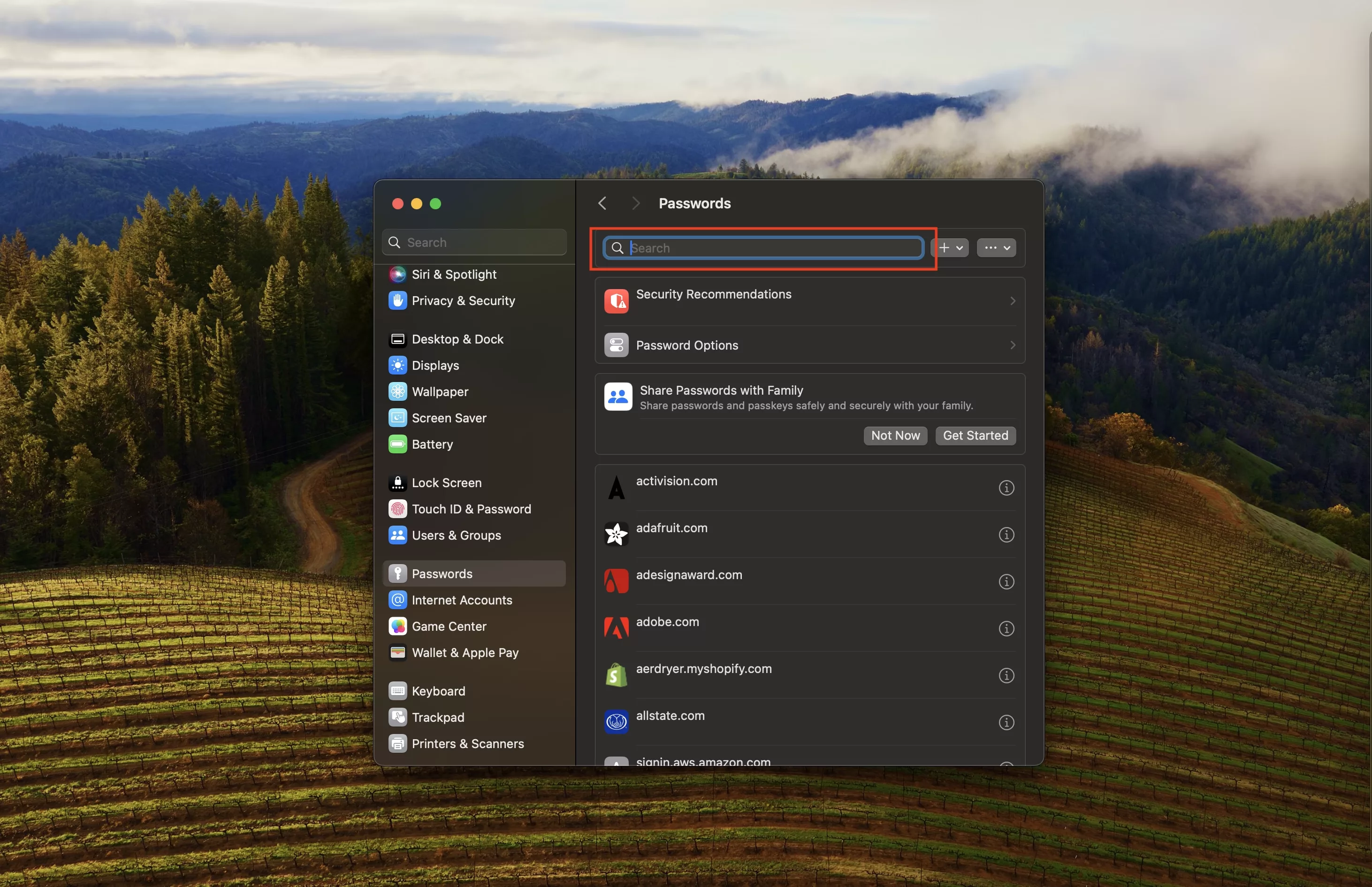 A screenshot of a MacBook desktop showing the System Settings app with the password manager open. Highlighted at the top in the center is the search field.