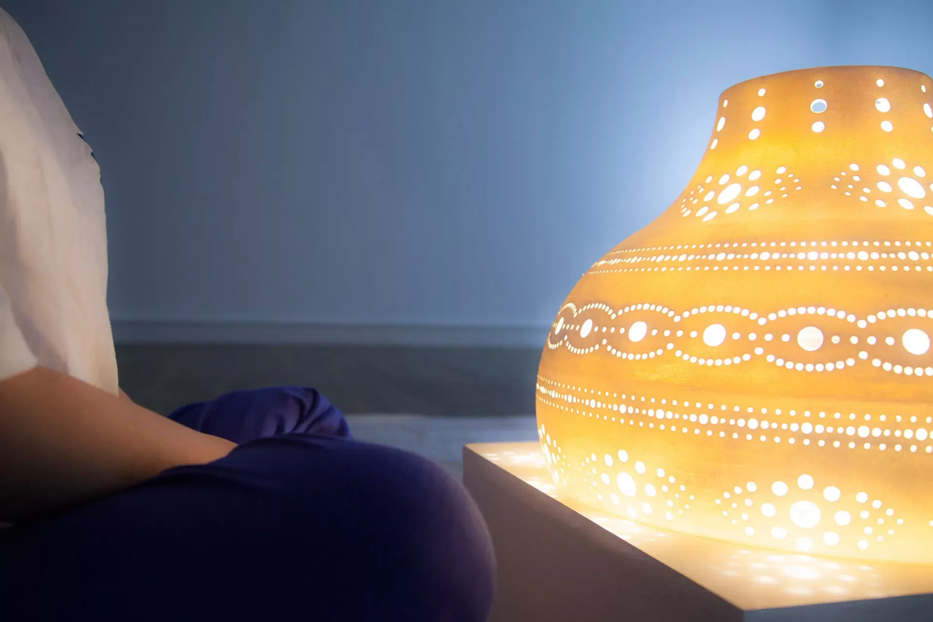 An individual meditating over a Solace lamp which changes its brightness to match an individuals breath.